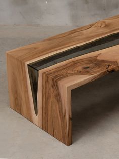 a wooden bench made out of wood with glass in the top and bottom section, sitting on concrete flooring