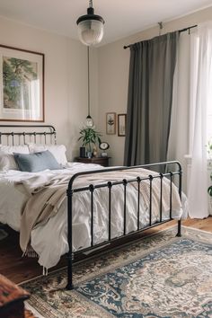 a bedroom with a metal bed frame and rug on the floor next to a window