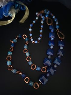 This is a very long ethnic style necklace made with large square dragon venis agate stones dyed blue. The necklace is asymmetrical with copper-plated brass decorative elements. To finish the necklace I used agate stones in different shapes. The necklace in the classic chain necklace style, very suitable for a single color dress or winter sweater. For those who love elegant retro style. All jewels are delivered in a decorated box, ready to be given as a gift to your loved one. How to take care of your jewellery: put on your beauty products (cosmetics, perfumes, ...) before wearing your precious jewel. Clean your jewelry with a soft cloth after wearing. Don't use water. Make sure you store your jewelry separately to avoid scratching it. Store away from heat sources, in a dry place in the spe Handmade Blue Fusion Necklaces, Blue Handmade Fusion Style Necklace, Handmade Blue Fusion Style Necklace, Handmade Blue Fusion Necklace, Rectangular Blue Necklace With Natural Stones, Blue Rectangular Natural Stone Necklace, Handmade Blue Rectangular Necklace, Bohemian Blue Rectangular Necklace, Handmade Blue Long Necklace For Gift