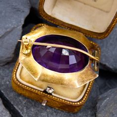 This circa late-Victorian era, 14k yellow gold statement brooch features an elongated octagonal border with an engraved design.  The brooch is centered with an oval cut amethyst, weighing 47.15 carats, in a full bezel setting. The bezel is surrounded by a silver-filled, floral detailed border. The brooch measures 31.3mm tall by 37.8mm wide and is finished with a 14K yellow gold hinged and locking pin back.  The brooch has a gorgeous patina.  There is a tiny dent that cannot be seen while worn. Oval Yellow Gold Brooches With Gemstone, Victorian Yellow Gold Brooches With Gemstone, Antique Cabochon Brooch For Formal Occasions, Antique Cabochon Brooch For Formal Wear, Yellow Gold Art Deco Brooches For Formal Wear, Art Deco Yellow Gold Brooches For Formal Occasions, Art Deco Yellow Gold Formal Brooches, Formal Art Deco Yellow Gold Brooches, Heirloom Oval Gemstone Brooches