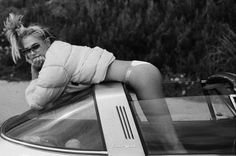 a woman leaning on the hood of a car