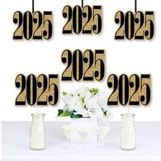 a table topped with vases filled with white flowers and two black numbers next to each other