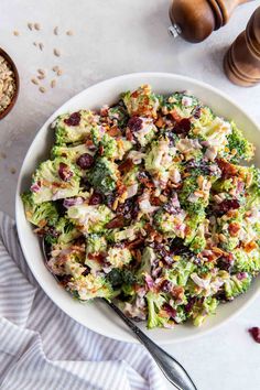 a white bowl filled with broccoli salad next to a spoon