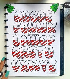 a hand holding a notebook with christmas lettering on it