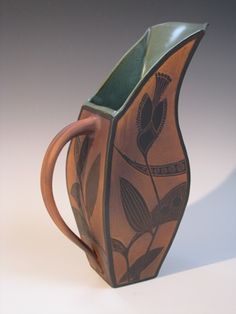 a brown and green vase sitting on top of a table