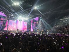 a large group of people standing on top of a stage with bright lights and confetti in the air