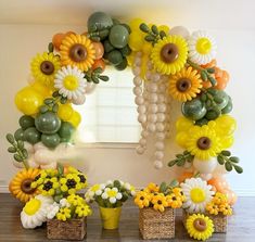 a table topped with flowers and balloons in front of a window