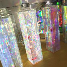 three clear vases sitting on top of a wooden table covered in holographic material