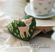 a heart shaped brooch sitting on top of a table next to a cup and saucer