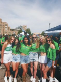 a group of young women standing next to each other in front of a crowd wearing green shirts