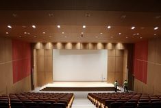 an empty auditorium with rows of seats and a projector screen on the wall behind it