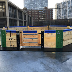 a large wooden box filled with blue and green plastic tubs next to tall buildings