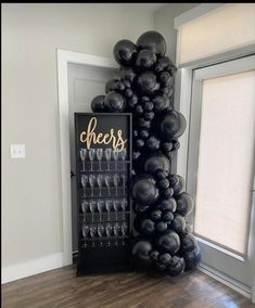 there is a black balloon tower with champagne glasses in it and cheers sign on the wall