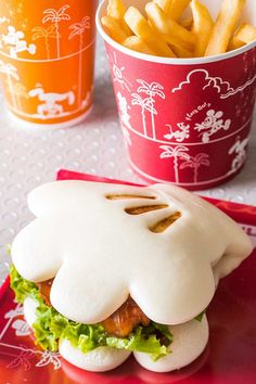 a sandwich and french fries are on a red plate next to two cups with drinks