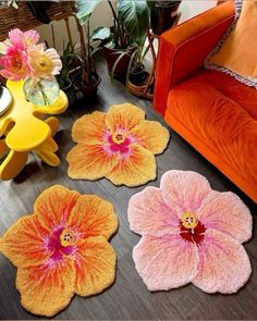 three flower rugs on the floor in front of a couch and table with flowers