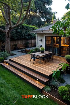 a backyard deck with steps leading up to the dining table and seating area, surrounded by greenery