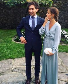 a man in a suit and tie standing next to a woman wearing a blue dress