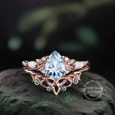 a ring with an aqua blue topazte and diamonds on it sitting on a rock