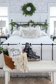 a bedroom with a white brick wall and black iron bed frame, decorated for christmas