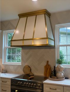 a stove top oven sitting inside of a kitchen next to two windows and a window