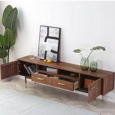 a wooden table with two drawers and some vases on top of it next to a potted plant