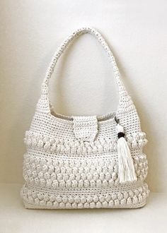 a white crocheted purse with a tasselled handle