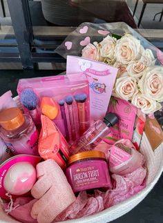 a pink basket filled with lots of beauty products next to white roses and other items