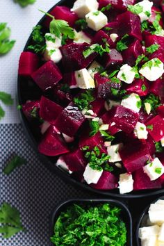 a bowl filled with beetroot and feta cheese salad next to two black bowls