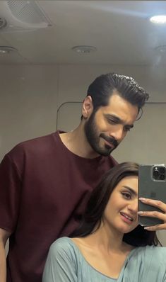 a man and woman taking a selfie in front of a mirror with their cell phone