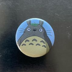 a button with a totoro on it is sitting on a black counter top