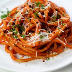 a white plate topped with pasta covered in sauce and parmesan sprinkles