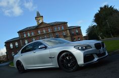 a white car parked in front of a building with a clock tower on it's side