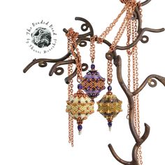 three beaded ornaments hanging from a tree branch