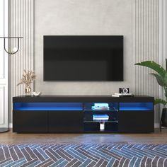 an entertainment center with a large television mounted on it's wall and illuminated shelves