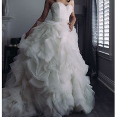 a woman in a wedding dress standing by a window