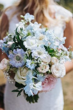 a bride holding a bouquet of white and blue flowers