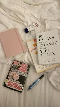 some books and pens are laying on a bed