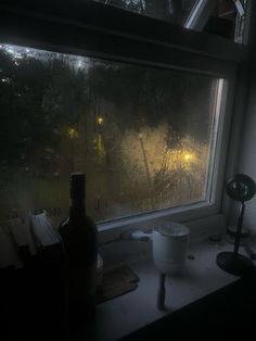 a window that has rain on it and some bottles in the window sill next to it