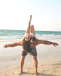 a man and woman are doing acrobatic tricks on the beach