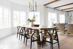 a dining room table with chairs and a potted plant in the center is surrounded by windows