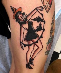 a woman wearing a witches hat and black dress on her thigh, with the word love tattoo parlou