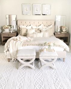 a white bed with lots of pillows on top of it and two mirrors above the headboard