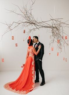 a man and woman standing next to each other in front of a tree with branches