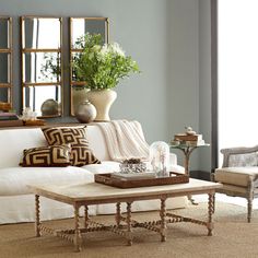 a living room with white couches and mirrors on the wall above them is shown