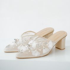 a pair of white shoes with flowers and pearls on the heel, all in satin material