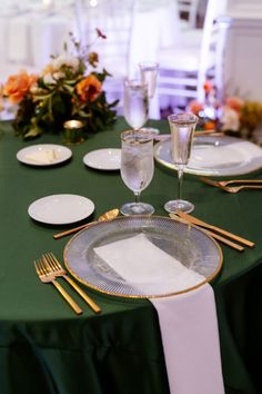 the table is set with plates, silverware and gold utensils on it