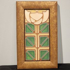 a wooden frame with stained glass in the center on a black table next to a white wall