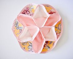 a pink and yellow plate with folded napkins in the shape of an origami flower