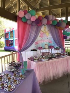 an outdoor party with balloons, cake and cupcakes