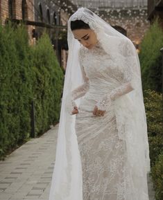 a woman in a wedding dress and veil is walking down the street with her hand on her hip